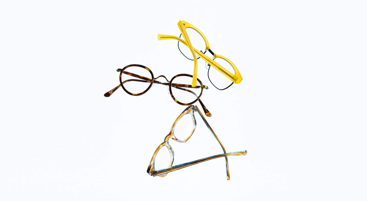 3 pair of eyeglasses from different angles sitting on flat surface.