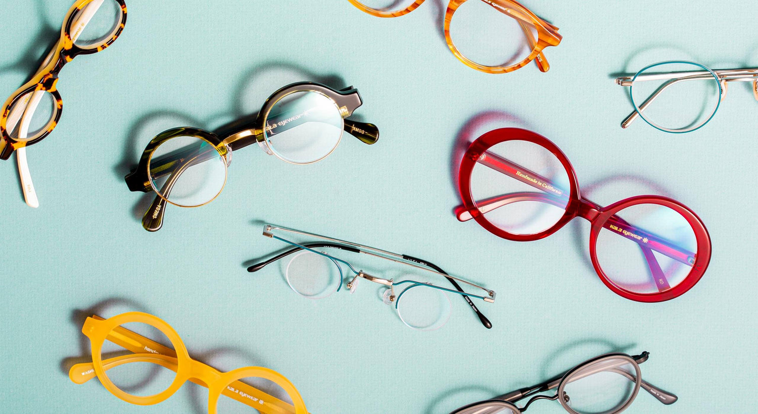overhead image of round eyeglasses scattered against robins egg blue background.